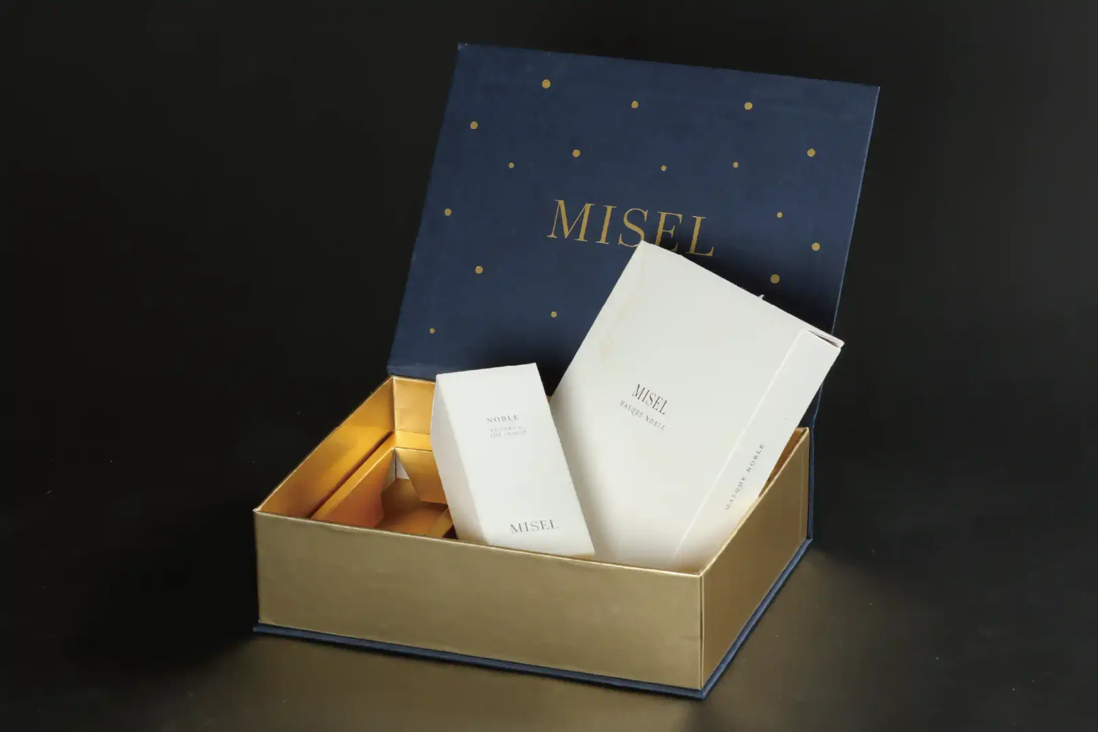 打開嘅 MISEL 書型盒,盒蓋內側燙金 Logo 同星點,兩件護膚品企喺金色內盒