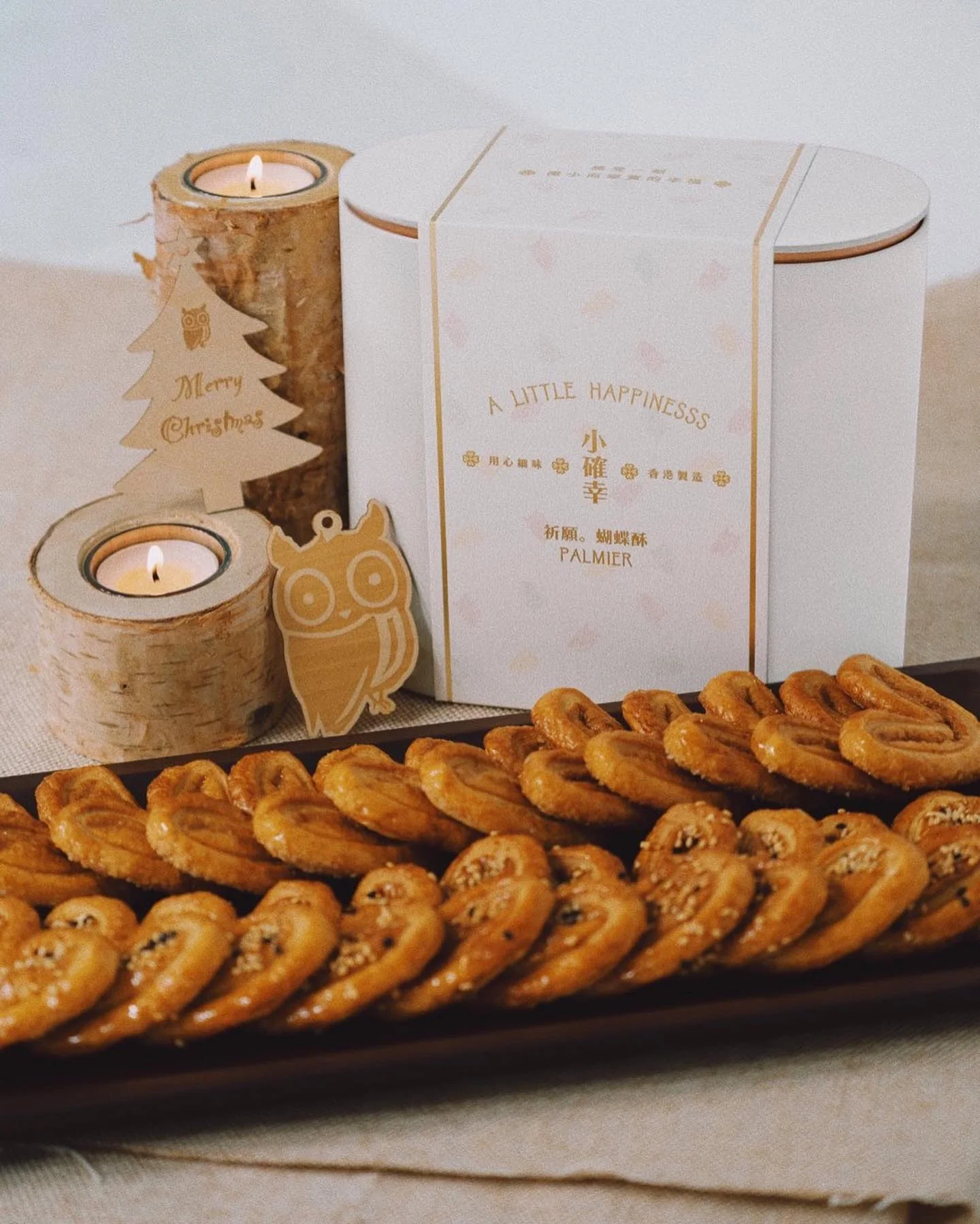小確幸白色蝴蝶酥盒套聖誕圍條，旁邊有木製 Merry Christmas 聖誕樹掛牌、貓頭鷹掛牌同蠟燭